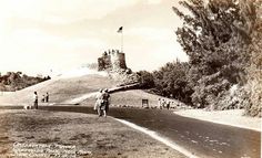 an old black and white photo of people standing on the side of a road in front of a castle