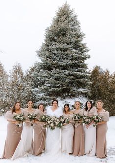 a group of women standing next to each other in front of a snow covered tree