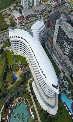 an aerial view of a large white building in the middle of a green area with lots of trees and buildings around it