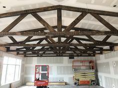 the inside of a building that is being built with wood beams and construction equipment on it