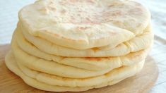 a stack of pita bread sitting on top of a wooden cutting board