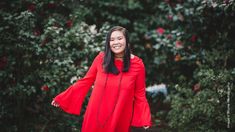 a woman in a red dress is smiling and posing for the camera with her arms outstretched