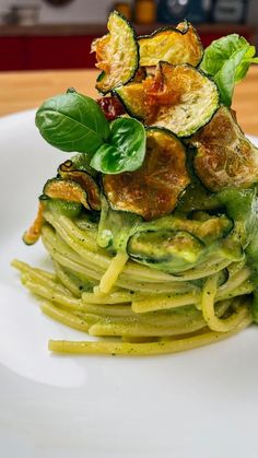 a white plate topped with zucchini and spinach covered in pesto sauce