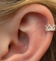 a close up of a person's ear with a small crown on the side