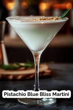 a martini glass filled with white liquid and topped with pistachio blue bliss martini