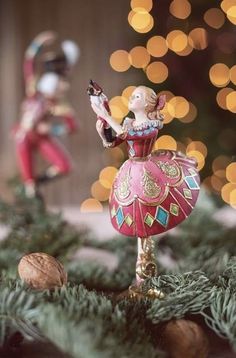 two figurines on top of a christmas tree with lights in the back ground