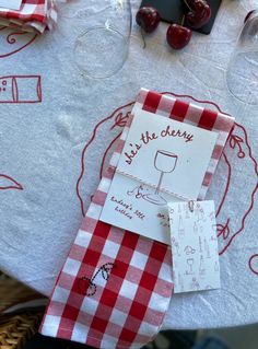 a table topped with red and white checkered napkins next to glasses of wine