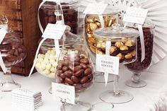 there are many different types of candies in glass jars on the table with tags