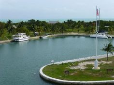 an island in the middle of a body of water surrounded by palm trees and boats