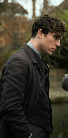 a man in a suit and tie standing next to a bird statue looking at something