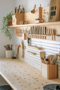 a wooden desk topped with lots of crafting supplies on top of a white wall