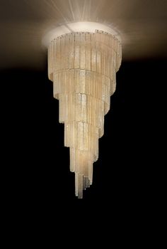 a chandelier hanging from the ceiling in a dark room with light coming through it