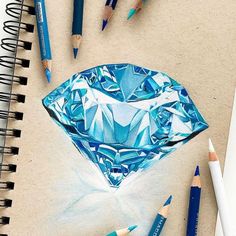 several colored pencils are laying next to an origami shaped paper with a blue diamond on it