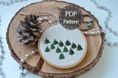 a cross stitch pattern with pine trees and snow on the ground next to some beads