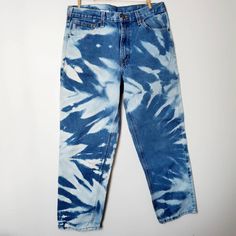 a pair of blue jeans with white and black tie - dye on them, hanging up against a wall