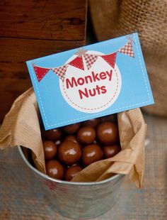 a bucket filled with lots of chocolate covered candies next to a sign that says monkey nuts