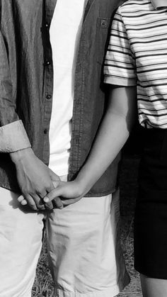 two people standing next to each other holding hands