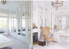 the interior of a white bedroom with mirrored closet doors and chandelier hanging from the ceiling