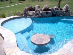 an outdoor pool with stone steps leading up to it and a fire pit in the middle