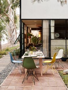 an outdoor dining area with tables and chairs in front of a building that has trees on it