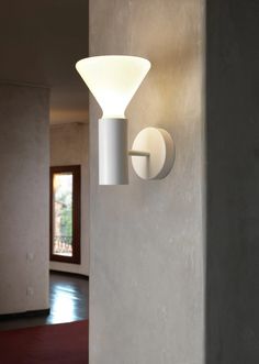 a white wall light mounted on the side of a gray wall next to a doorway