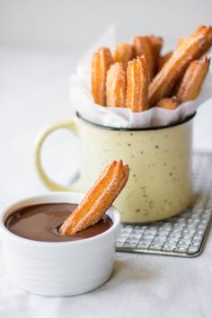 there is a cup of chocolate and some churros