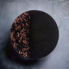 a black and gold plate on a blue cloth with brown sprinkles in the center