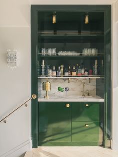 a green cabinet in the corner of a room with bottles and glasses on it's shelves