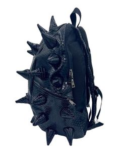 Black Out black backpack is your ticket to making an unforgettable statement. This black backpack's bold spike design and faux reptile texture commands attention and exudes confidence that sets you apart from the crowd. EXTERIOR Dimensions: 18" x 14" x 8" • Two zipper side pockets • Ergonomic mesh extra back padding • Adjustable Straps with chest strap for custom sizing • Heavy duty zippers with metal hardware • Top loop for hanging INTERIOR Padded laptop compartment protects electronics • Fits