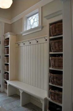 a white bench sitting under a window next to a shelf filled with wicker baskets