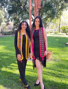 two women standing next to each other in the grass