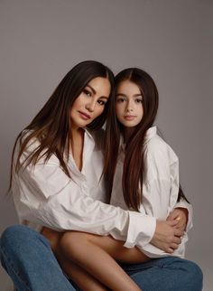 two young women sitting on top of each other posing for the camera with their arms around one another