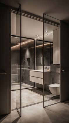 an empty bathroom with glass walls and mirrors on the wall, along with a toilet and sink