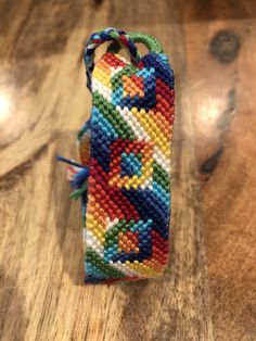 a cell phone case made out of multicolored beads on a wooden table top