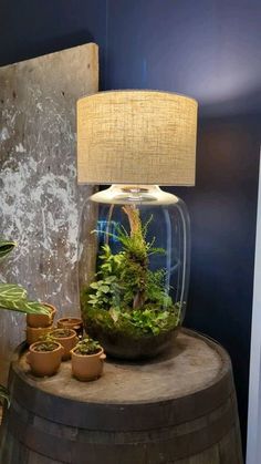 a lamp that is on top of a wooden barrel with plants in it and some potted plants