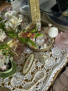 a table topped with vases filled with flowers next to a mirror and other items