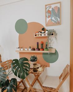 a table with two chairs and a potted plant on it in front of a wall