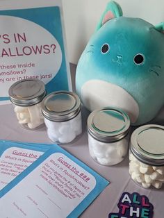 a stuffed animal sitting on top of a table next to jars filled with marshmallows