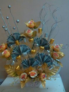 a vase filled with lots of different types of flowers next to silver and gold decorations