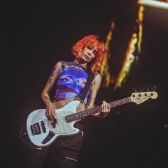 a woman with red hair is playing an electric guitar