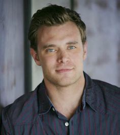 a man wearing a blue and red shirt posing for a photo with his hands in his pockets