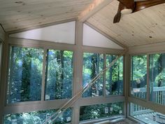 the inside of a house with large windows and wooden ceiling fan in it's center