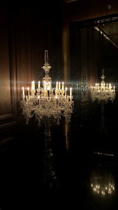 a chandelier is lit up in the dark with many lights on it and some mirrors behind it