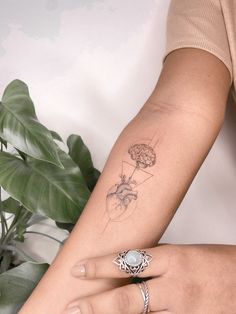 a woman's arm with a tattoo on it and a plant in the background