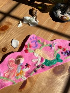 a pink rug with flowers on it sitting on top of a wooden table next to other items