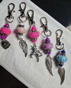 several charms are displayed on a white napkin with pink beads and silver angel charms