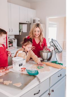 a woman and two children making cookies in the kitchen