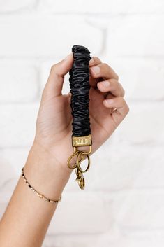 a person holding up a black umbrella with gold hardware on it's end and a keychain attached to the handle