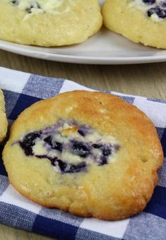 blueberry muffins sitting on top of a checkered table cloth next to two plates