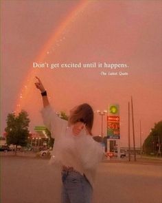 a woman standing in front of a rainbow with a quote on it that says don't get excited until it happens